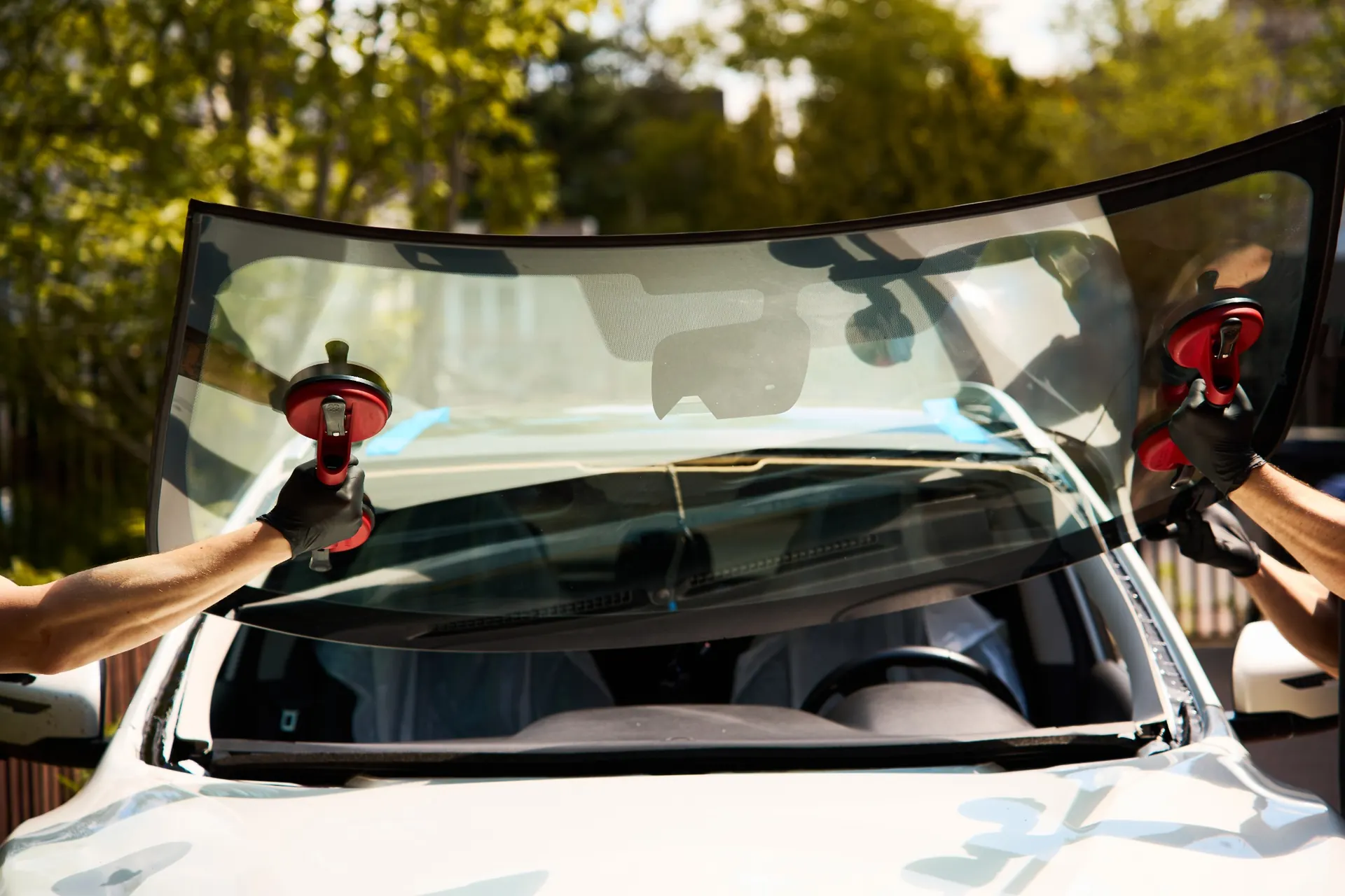 Auto glass technicians carefully installing a replacement windshield on a vehicle